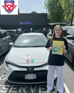 A young woman in a black T-shirt and white pants holds a yellow form and a green N sign beside a white car outside a Driver Licensing office.